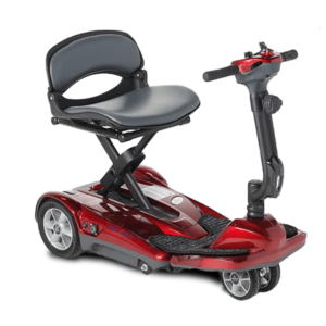 A compact, red, four-wheeled mobility scooter with a cushioned seat, adjustable armrests, and a tiller featuring simple control buttons. The scooter has a footrest and is designed for easy maneuverability, suitable for indoor and outdoor use.