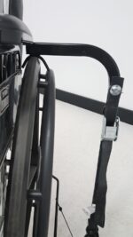Close up of the Tilt N Tote hold down arm and cam buckle securing strap over the rear wheel