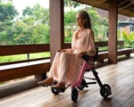 Woman riding the Enhance Mobility Roamate in electric wheelchair mode outdoors